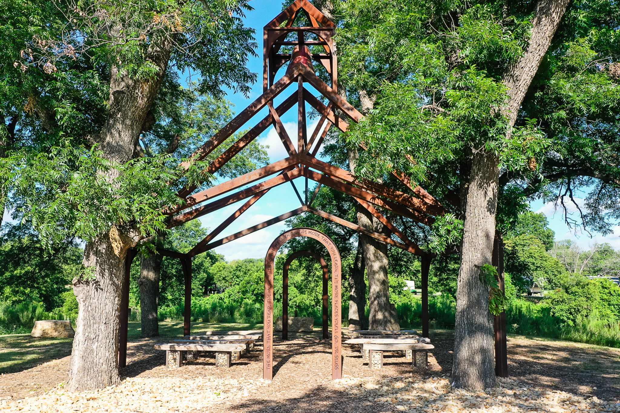 Picture of a metal outdoor classroom with trees around it